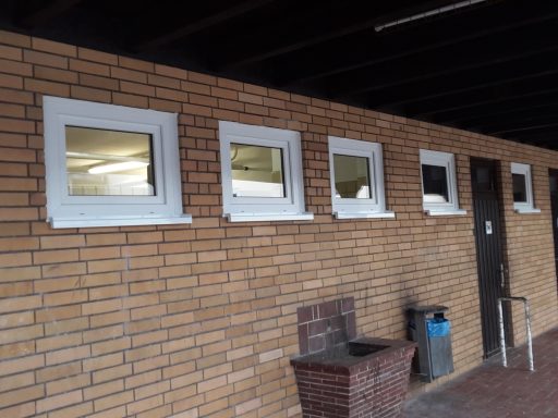 Fenster in einer Ziegelwand, mit weißem Rahmen, und einer Tür daneben.