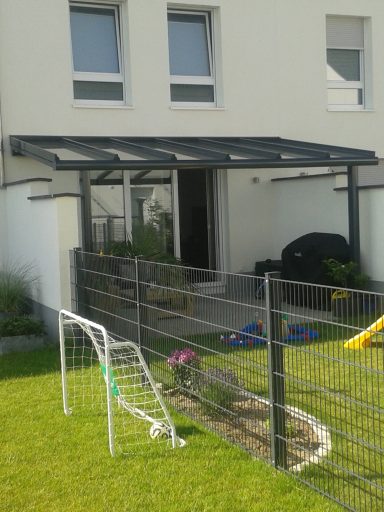 Modernes Haus mit überdachtem Eingang, Garten und Fußballtor im Vordergrund.