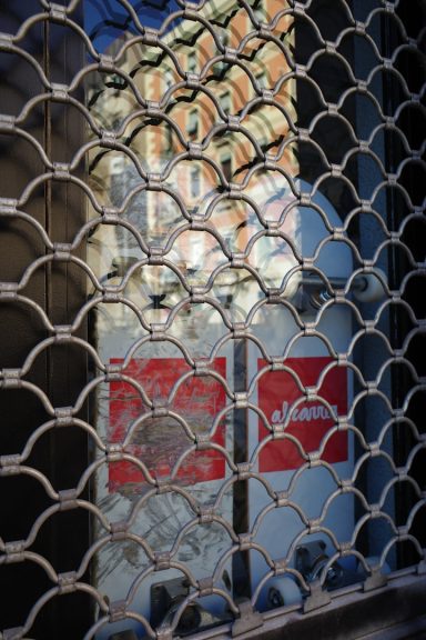 Gitter vor einem Schaufenster mit reflektierenden Gebäuden im Hintergrund.